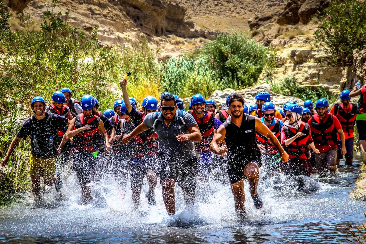 A big Adventure Plus group charging through the river in life jackets and helmets
